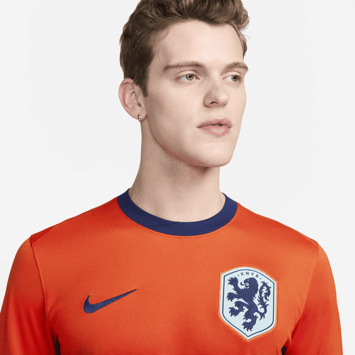 fcf4f737_5406_47cb_8e44_0fe17182e5a1 | UAE SPORT STORE Portrait of a young man wearing an orange soccer jersey with a blue collar and a lion crest on the chest.