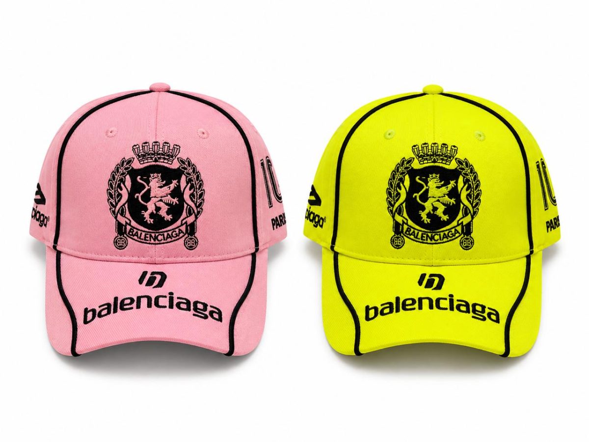 Two Balenciaga baseball caps in pink and neon yellow with black crest and ‘balenciaga’ branding visible on the bill and sides.