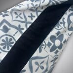 Close-up of white fabric with a blue floral pattern and a dark navy seam running diagonally across the image.