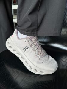fe935211-68bf-42b5-954a-b48742580a00 | UAE SPORT STORE Light gray On running shoe on a person’s foot, showing a chunky white sole and knit upper with the logo visible.