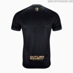 Black athletic jersey with a subtle pattern, gold crest at the neckline, and gold lettering near the bottom reading 'OUTLIER' (sportswear style).