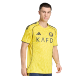 Young man wearing a bright yellow Adidas soccer jersey with black trim and 'KAFD' sponsor on the chest.