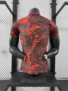 Back view of a red and black patterned athletic shirt on a mannequin torso, standing on a gym bench against a metal mesh wall.