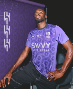 Athlete in a purple SAVVY Games Group jersey posing with one hand on his hip against a purple backdrop