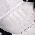 Close-up of a white textured shirt collar with a visible size label, showing intricate jacquard pattern in the fabric.