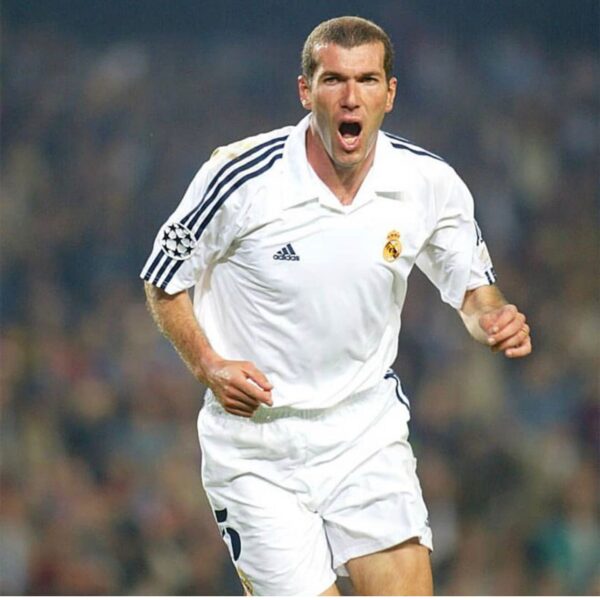 Soccer player in a white Real Madrid jersey celebrates on the field, mouth open in a yell, during a match.