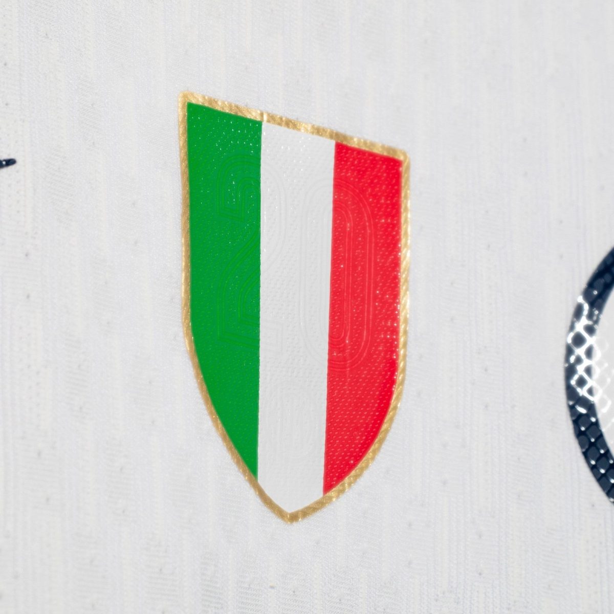 Decorative shield patch displaying the Italian flag (green, white, red) with a gold edge on white fabric