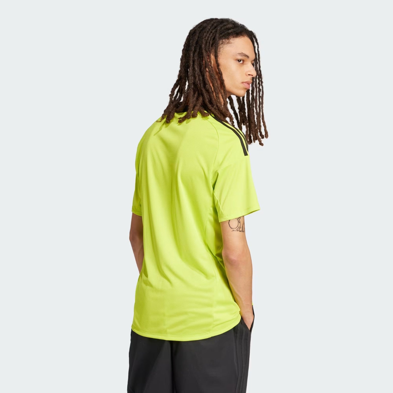 g76CEThVhjO1xk5 | UAE SPORT STORE Person with long dreadlocks wearing a bright lime-green T-shirt, seen from the side with a pale background.