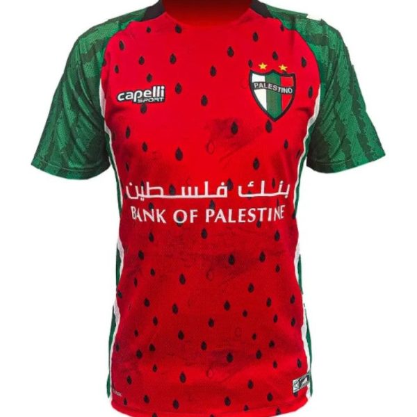 Red football jersey with green sleeves and side panels, featuring Bank of Palestine sponsor text across the chest and a Palestine crest on the left.