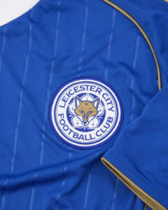 gu05qitjf9dtco5lrkni | UAE SPORT STORE Leicester City Football Club badge on a blue striped jersey with gold piping.