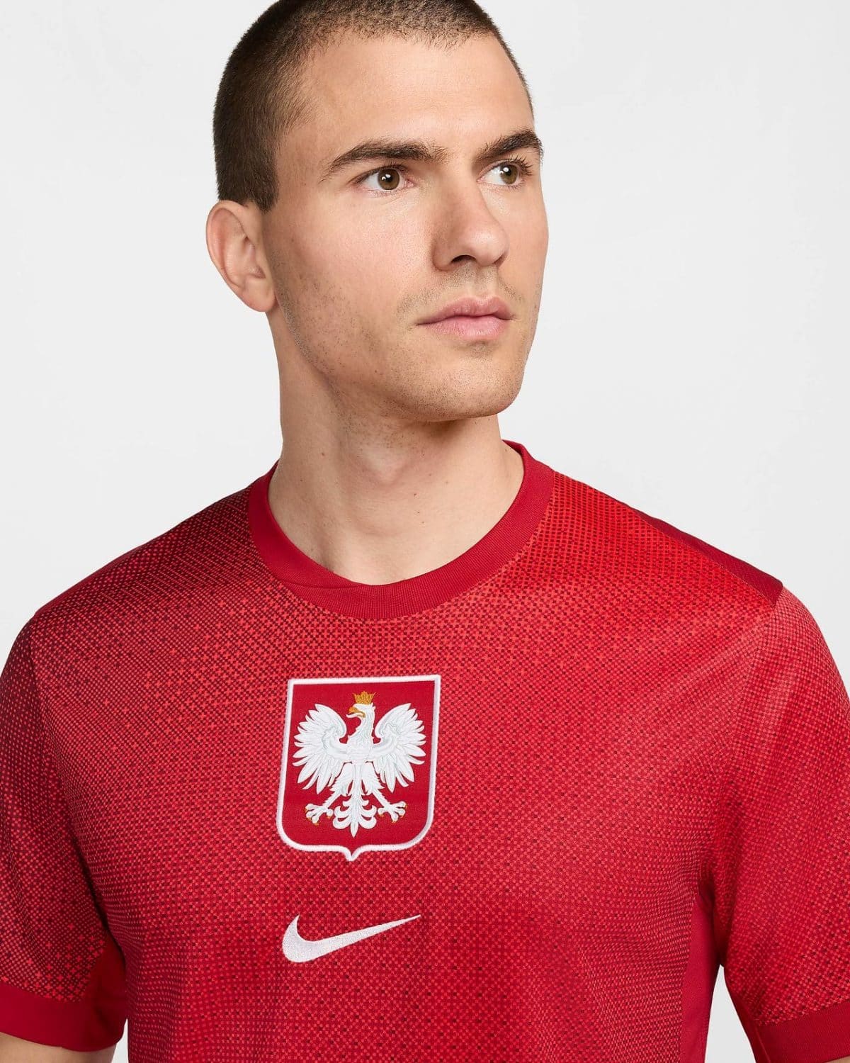 Portrait of a man in a red Poland national football team jersey with a white eagle crest and Nike logo','Close-up of a man wearing a red Poland soccer jersey featuring the white eagle emblem.