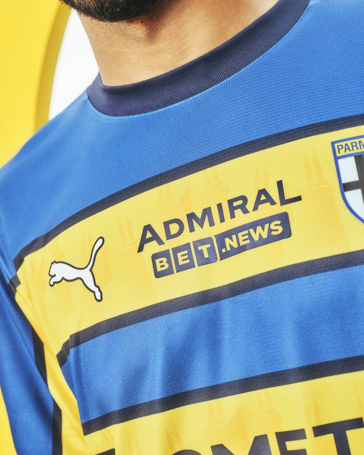 Close-up of a blue and yellow sports jersey with the sponsor banner 'ADMIRAL BET NEWS' and a small Puma logo