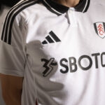 hDdvLMnsQAH5Eti | UAE SPORT STORE Close-up of a white soccer jersey with Adidas logo and SBOTOP sponsor, partial club crest on the chest.