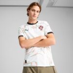 hTE2Rww96F4BBet | UAE SPORT STORE Young man posing with arms crossed, wearing a patterned Portugal football jersey and black-trimmed collar against a gray background.