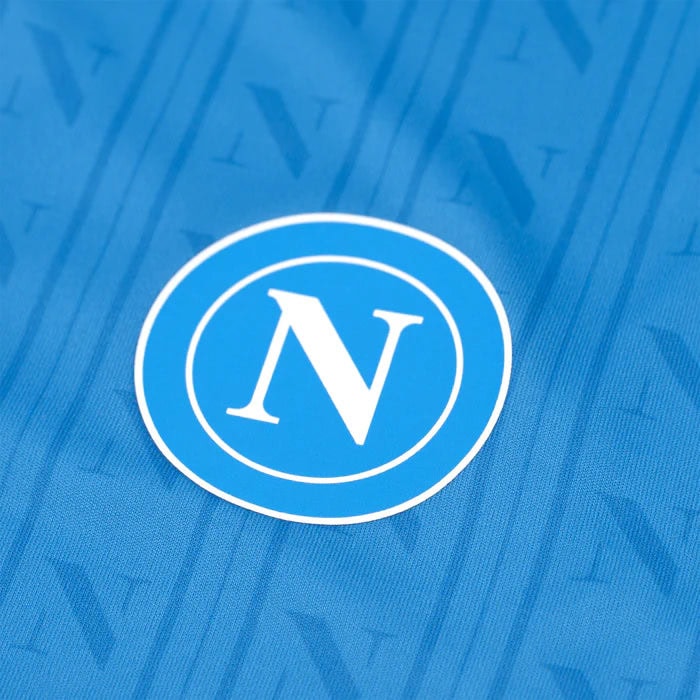 home-shirt-replica-1600-x-1600-px_07 | UAE SPORT STORE Close-up of blue fabric with a white circular logo featuring the letter N inside two rings.