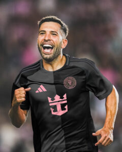 hq50kX1xcW0hAZc | UAE SPORT STORE Soccer player celebrating on the field, wearing a black kit with pink logos and a crest, smiling and running with a clenched fist.