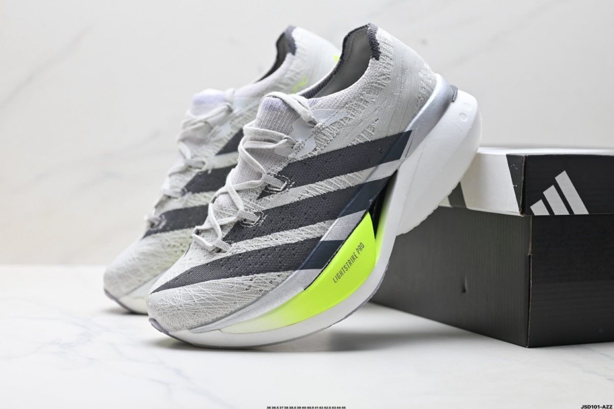 Gray knit-running shoes with a bright neon-yellow sole resting on a black shoebox.