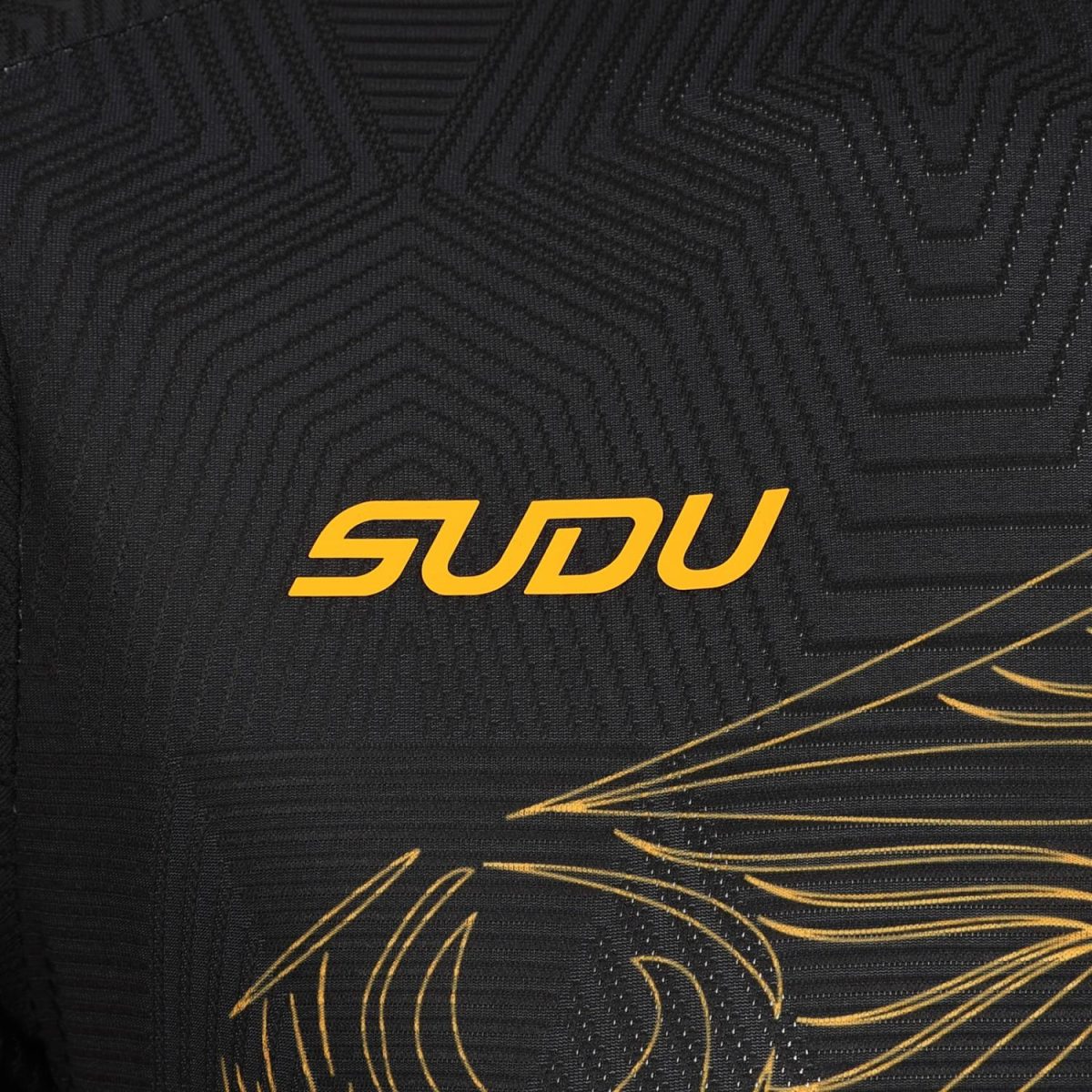 Close-up of black textured fabric with an orange 'SDU' logo and gold decorative lines.