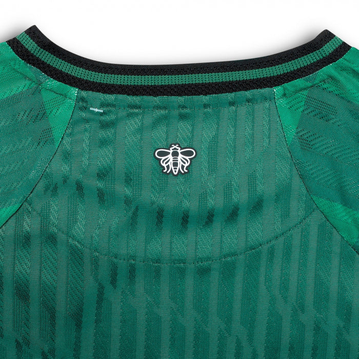 iklo | UAE SPORT STORE Green athletic jersey back neckline with a black-green striped collar and a small white bee emblem at the center of the collar area.