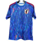 Blue Japan national football jersey with abstract neon streaks, crest on the left chest and red shoulder stripes.
