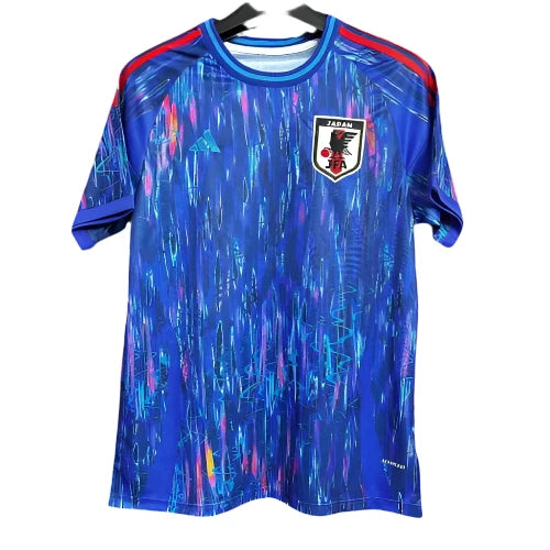 Blue Japan national football jersey with abstract neon streaks, crest on the left chest and red shoulder stripes.