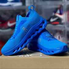 Pair of bright blue running shoes resting on a shoe box, showcasing a chunky textured sole and laces