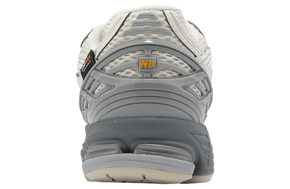 ipad_new-balance-1906r-beige-black-1 | UAE SPORT STORE Rear view of a gray and off-white running shoe showing the heel with a yellow NB logo on a gray plastic support panel.