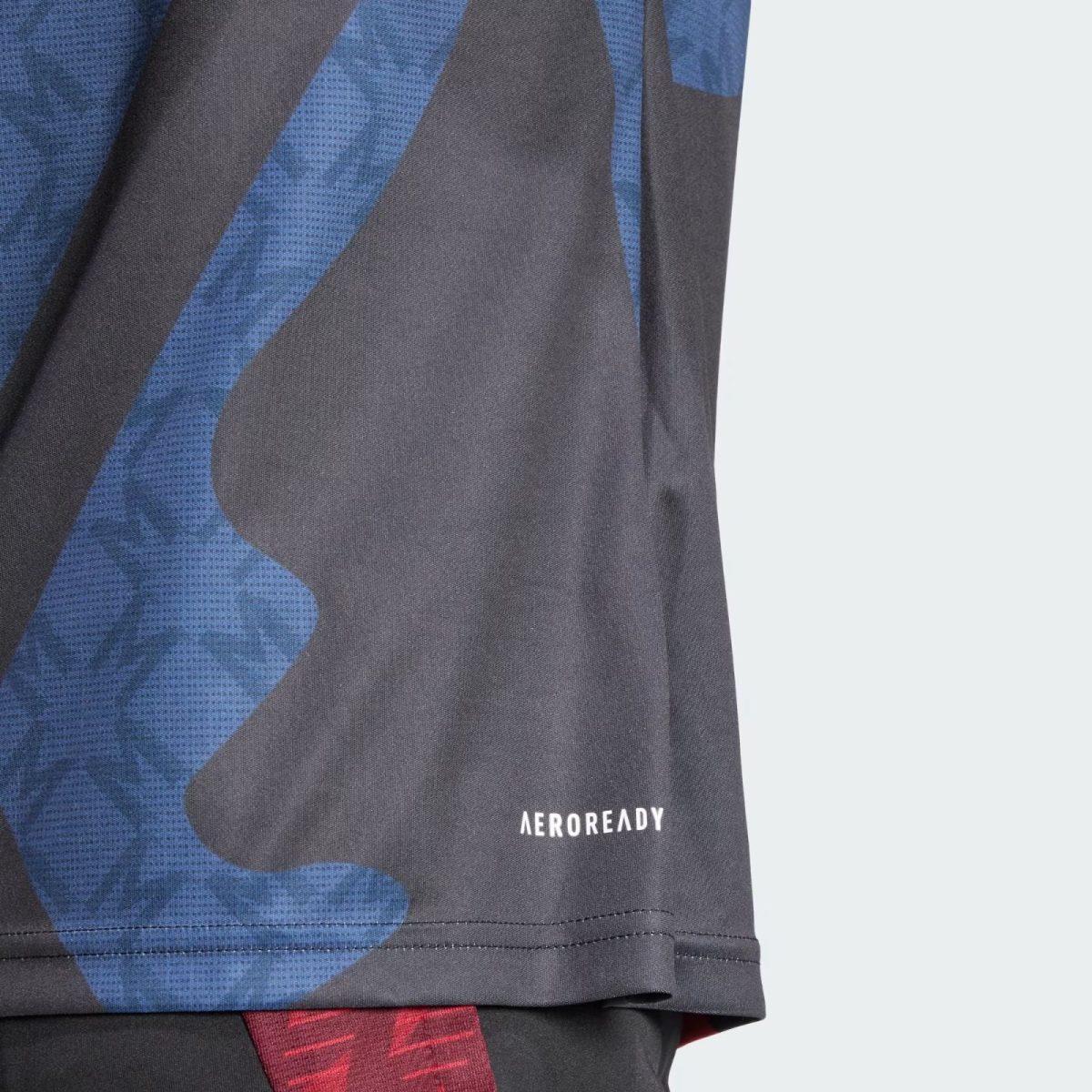 Close-up of blue and black camouflage athletic fabric with 'AEROREADY' branding visible on the hem edge