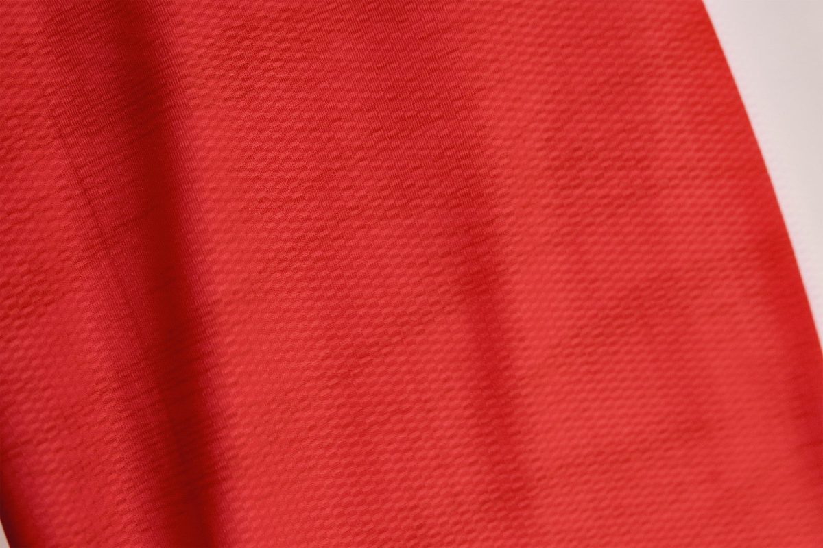 Close-up of red fabric with a fine textured weave and soft folds along the left edge.",