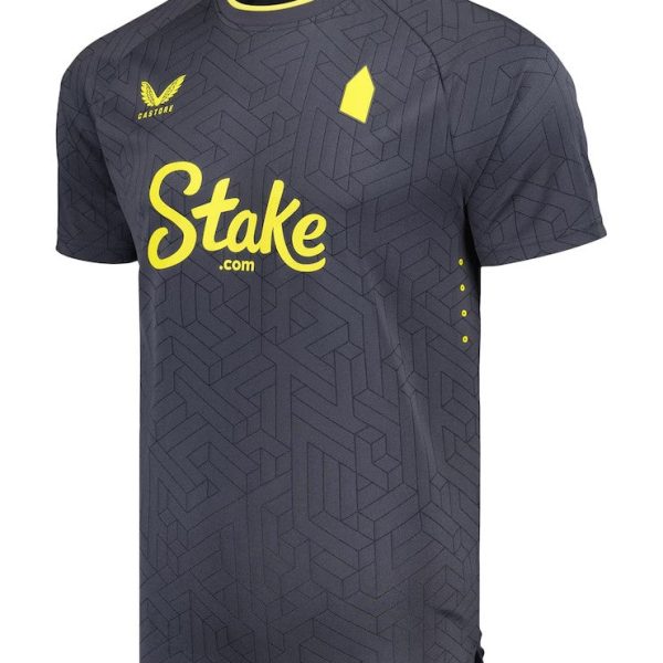 Dark gray sports jersey with a geometric pattern and neon yellow accents; Stake.com sponsor logo across the chest and Castore branding on the chest.
