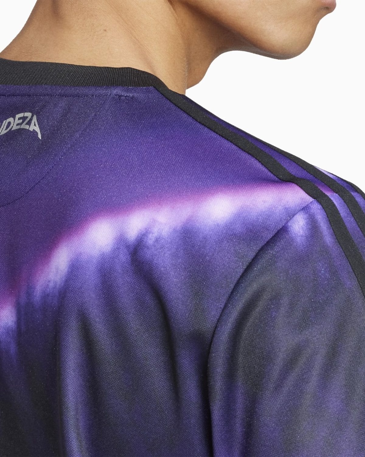 Close-up of a purple tie-dye jersey with a black seam along the shoulder and a hint of the wearer's neck.