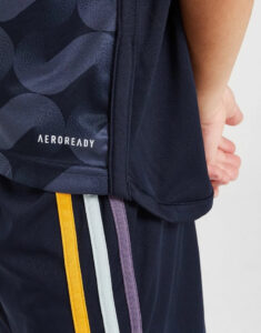 Close-up of a navy athletic jacket with the AEROREADY logo and color‑blocked yellow, white, light blue, and purple stripes on dark shorts/pants.