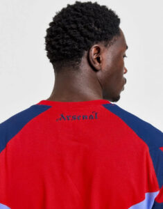 Back view of a person wearing a red and blue Arsenal jersey, with the word 'Arsenal' stitched at the neckline.