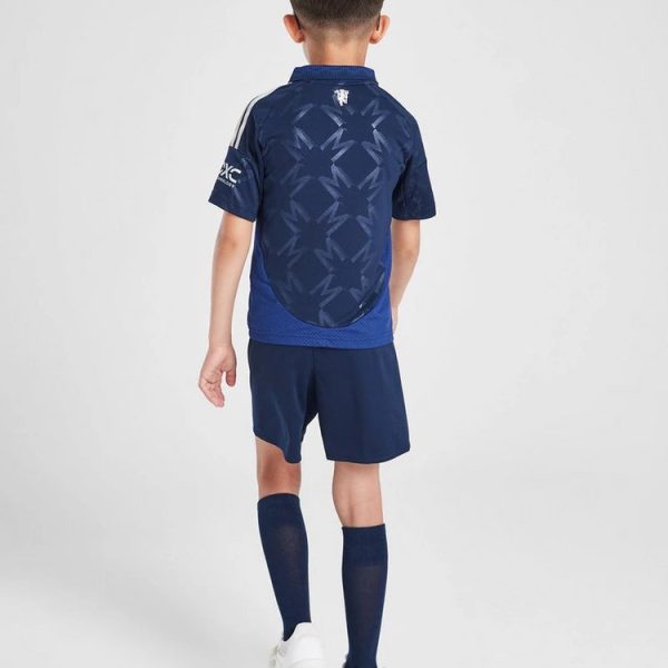 Back view of a child in a navy soccer kit with a patterned back panel, blue shorts and socks, and white shoes.
