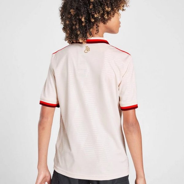 Back view of a light beige polo shirt with red trim on sleeves and collar; small gold logo near the neck.