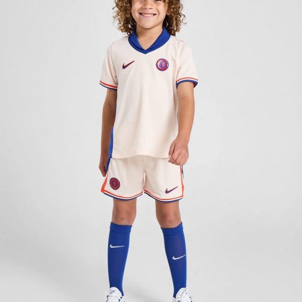 Child model wearing a cream PSG-inspired soccer kit with blue collar, blue accents, and blue socks, smiling at the camera.