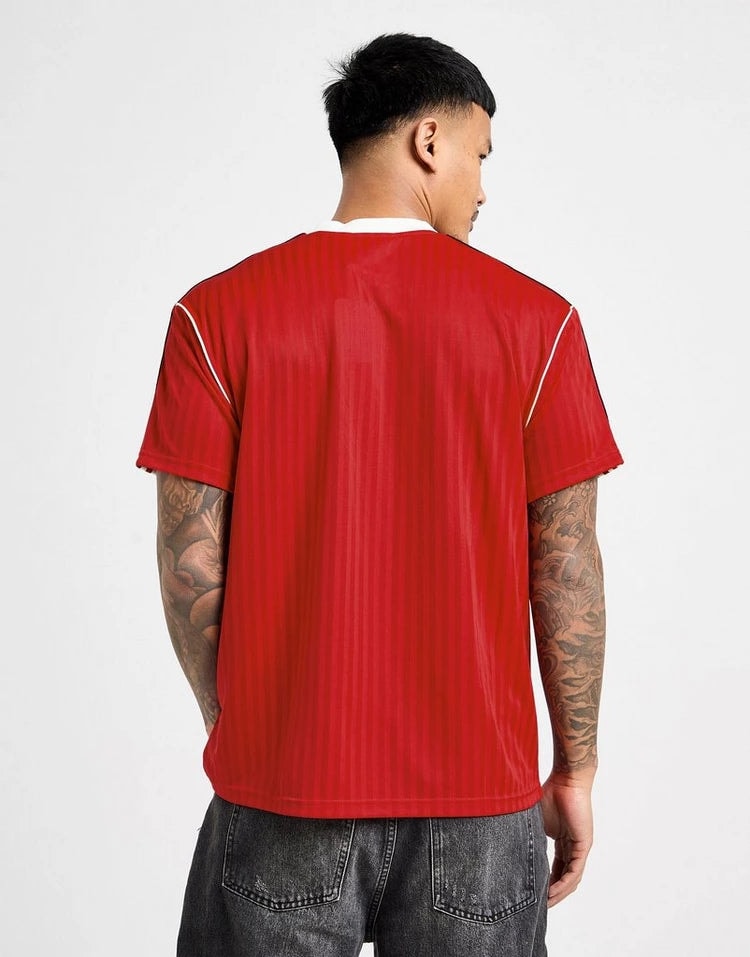 jd_749355_c | UAE SPORT STORE Back view of a man wearing a red athletic jersey with white piping, paired with dark jeans; visible arm tattoos.