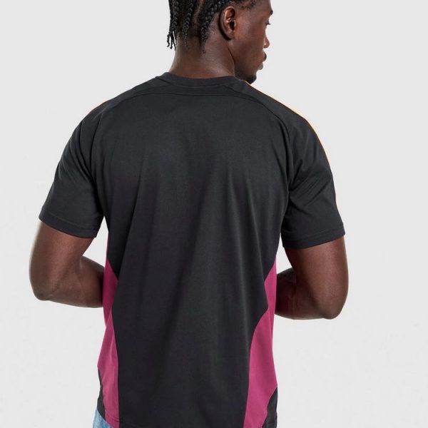 Man wearing a black T-shirt with magenta side panels, viewed from the back, paired with blue jeans.