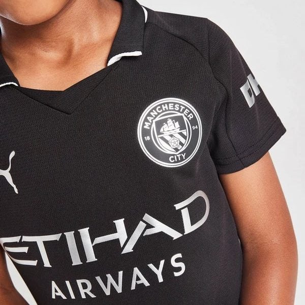 Close-up of a person wearing a black Manchester City jersey with the club crest and Etihad Airways sponsor logo visible.