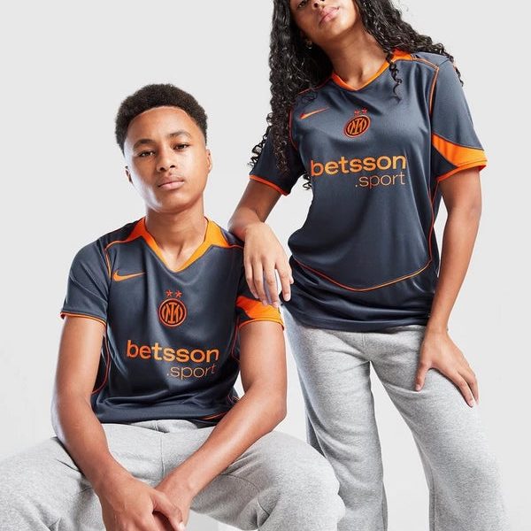Two young models wearing dark gray Inter Milan-style jerseys with orange trim and the 'betsson sport' logo, posing against a light background.