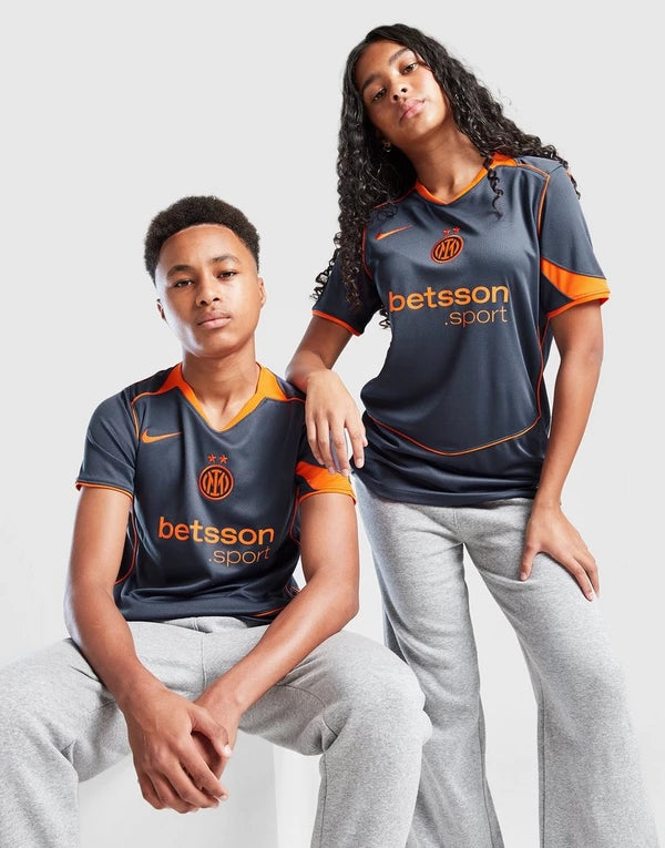 jd_762191_a | UAE SPORT STORE Two young models wearing dark gray Inter Milan-style jerseys with orange trim and the 'betsson sport' logo, posing against a light background.