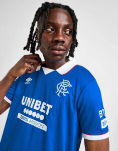 Portrait of a man in a blue Rangers football jersey, looking to the left, with the club crest and Unibet sponsor visible.