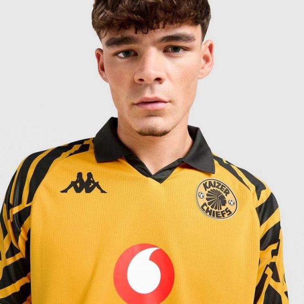 Young man wearing a yellow Kaizer Chiefs soccer jersey with Vodacom logo on the chest, facing the camera.