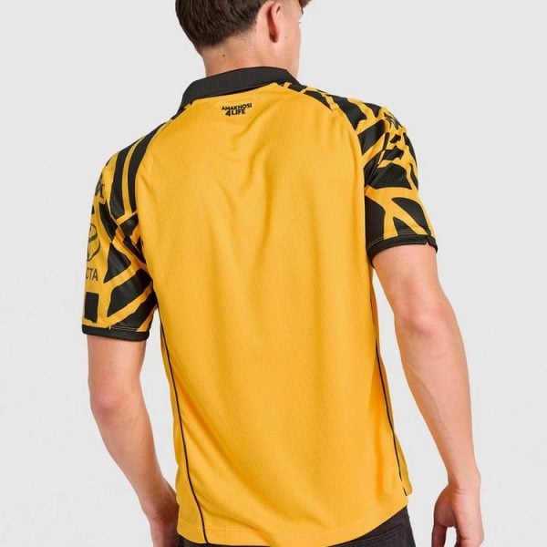 Back view of a person wearing a yellow sports jersey with black abstract patterns on the sleeves.
