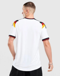 Back view of a man wearing a white football jersey with black, red, and yellow shoulder accents on the sleeves and collar edge.