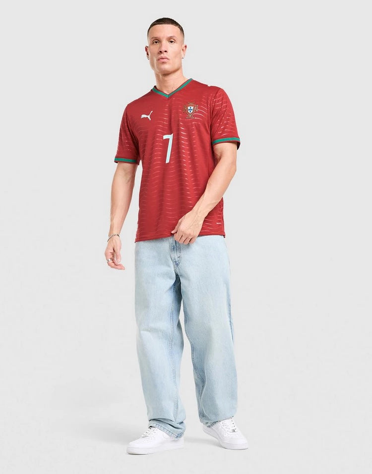 jd_778217_c | UAE SPORT STORE Male model wearing a red Portugal football jersey with number 7, paired with light-wash jeans and white sneakers on a light background.
