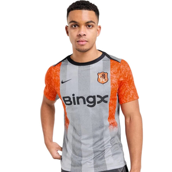 Young man wearing a gray striped soccer jersey with orange sleeves and Bingx sponsor logo, facing the camera.