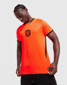 jd_789706_a | UAE SPORT STORE Man wearing a bright orange Netherlands soccer jersey with a black crest, looking down, against a light gray background.
