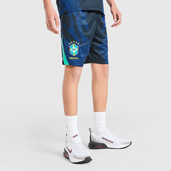 Athlete wearing Brazil national team soccer shorts with crest, white socks, and white sneakers, shown from knees down to feet.