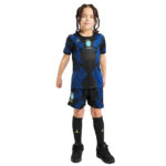 Young child wearing Brazil national team soccer kit—a blue and black patterned jersey with crest, matching shorts, and black socks, facing the camera.